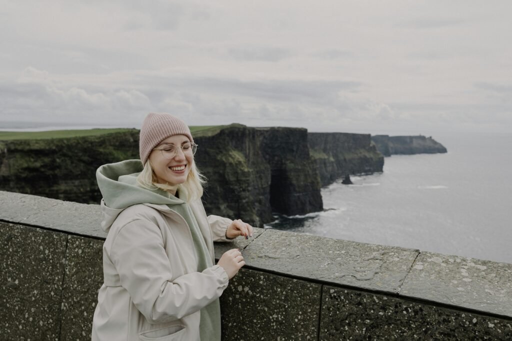 pexels-photo-23644188-23644188 A woman smiling by the Cliffs of Moher in Ireland, capturing the beauty of travel and nature.